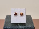 a pair of earrings sitting on top of a marble block