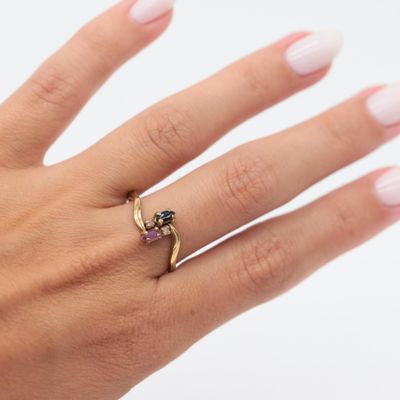the hand of a woman wearing a gold ring with a black diamond on it
