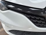 the front end of a white car with a denting dent on it