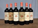 six bottles of red wine are lined up on a wooden table