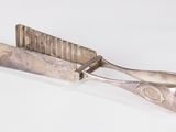 un petit objet argenté avec une poignée métallique sur une surface blanche