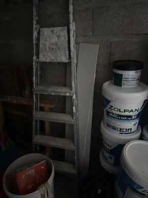 plusieurs seaux de peinture posés à côté d'une échelle dans une pièce
