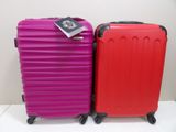 pair of red and pink suitcases sitting next to each other on a white surface