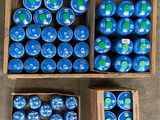 several boxes of blue and green plastic balls sitting on top of a cement floor