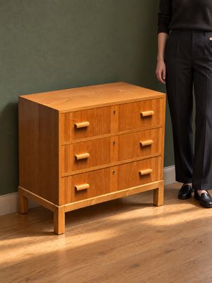 une femme debout à côté d'une commode dans une pièce