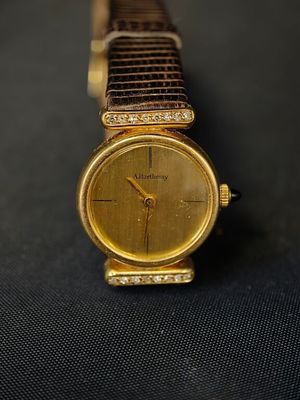 une image représentant une montre en or posée sur une surface noire