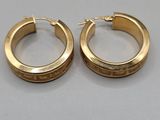 a pair of gold hoop earrings on a gray surface