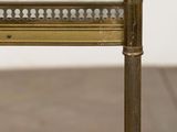 an antique brass and glass side table on a wooden floor
