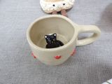 a small black cat in a coffee cup on a table