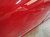 the side of a red car with the door handle missing