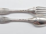 two spoons and a fork on a white surface