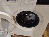 a white washing machine sitting on a pallet next to a glass container
