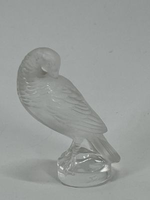 a glass figurine of a bird on a clear base