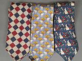 three different colored neck ties on a gray surface