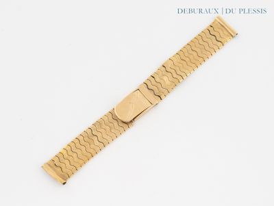 gros plan d'un bracelet en or sur une surface blanche