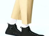 black high top sneakers with white socks and beige pants on a blue background