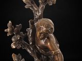 a bronze statue of a boy sitting on a tree branch