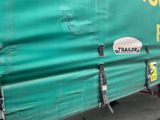 un gros camion vert avec une remorque accrochée sur le côté