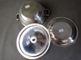 three silver dishes sitting on a table with labels on them