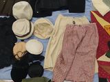 un lit sur lequel sont posés plein de vêtements et de chapeaux