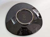 a black plate with a gold rim sitting on a white table