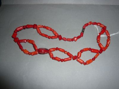 an image of a necklace made of red coral beads on a gray surface