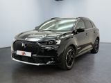 La voiture noire est garée dans une grande pièce au sol noir.