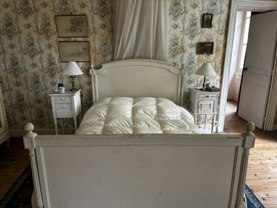 un lit blanc dans une chambre à coucher au papier peint à motifs floraux