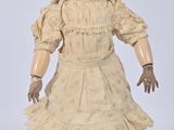 an old fashioned doll with brown hair and a white dress