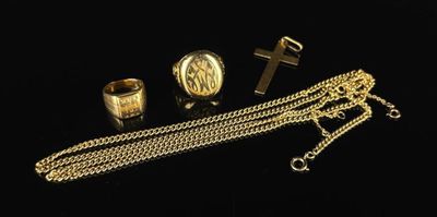 trois anneaux en or et une chaîne ornée d'une croix sur fond noir
