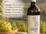une bouteille de vin posée sur une table, à côté d'un bol de raisins