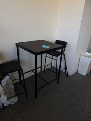 a small table and two stools in the corner of a room