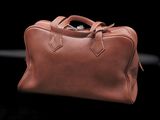 a brown leather bag sitting on top of a black surface
