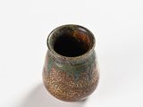 a close up of a small vase on a white surface