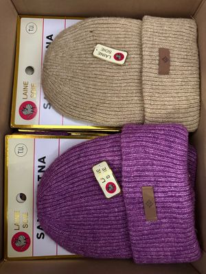 purple and beige knitted beanies in a cardboard box