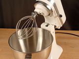 a white mixer with a metal bowl on a wooden table