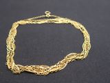 gros plan d'un bracelet en chaîne en or sur une surface noire