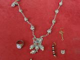 a close up of a necklace, bracelet, and ring on a red surface