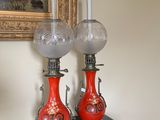 deux vases rouges posés sur une table noire, avec un tableau en arrière-plan