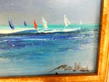 un tableau représentant des voiliers sur l'eau, dans un cadre doré