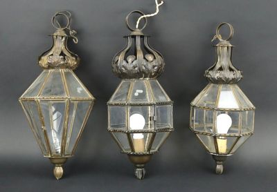trois lanternes en verre suspendues au plafond sur un fond gris