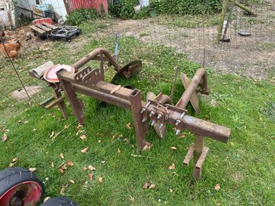a tractor plow sitting on the grass in the yard
