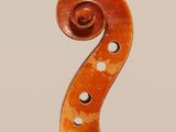 a close up of a violin neck with a fiddle in the background
