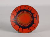 an orange plate with black designs on it on a white surface