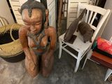 a statue of a woman sitting on a chair next to a chair