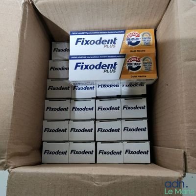 un carton rempli de boîtes de Fixdent
