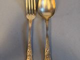 two silver spoons and a fork sitting on a table