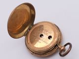 a gold pocket watch sitting on a white surface