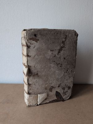 un vieux livre posé sur une table près d'un mur blanc