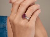 the woman is wearing a ring with a ruby stone in it